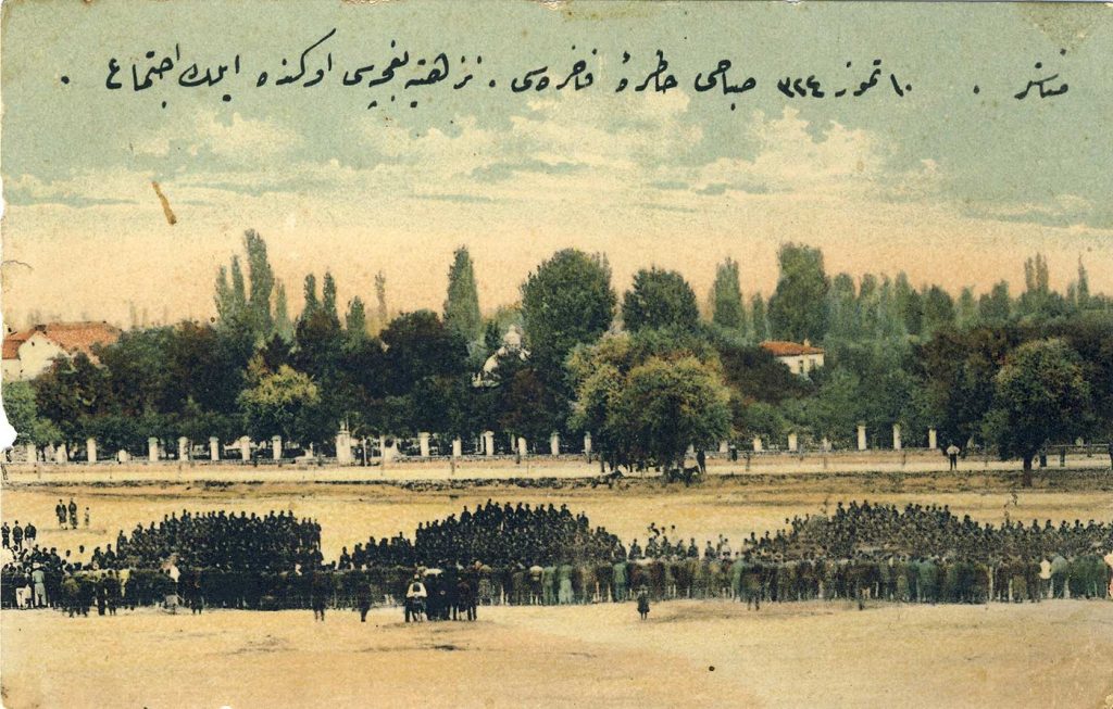 Полигонот на Третата турска армија, за вежби на војската. На истата се гледаат гледачи на трибините, пред смотра на војската. Во заднината е Железничката улица и паркот “Nuzhetiye” зад оградата, кој беше наречен Парк на слободата по 1908 година. Во средината на сликата се гледа и киоскот помеѓу дрвјата.
